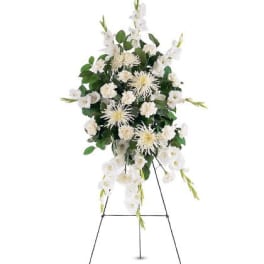 Tall white funeral spray of mums and carnations displayed on a metal easel stand