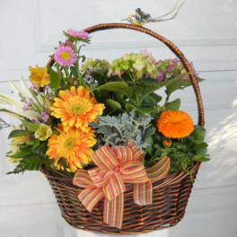 Basket of mixed flowers with a striped ribbon bow