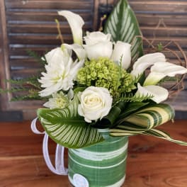 White roses and calla lilies arranged in a green striped container
