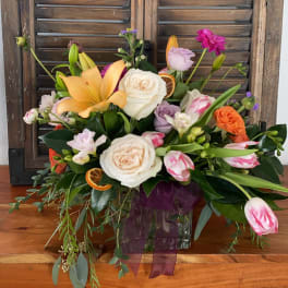 Mixed bouquet with roses, lilies, and tulips in a glass vase