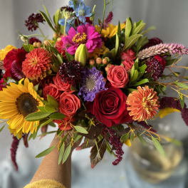 Handheld bouquet with sunflowers, roses, and mixed colorful blooms