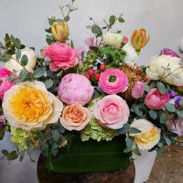 Mixed bouquet of pink, white, and yellow flowers in a green container
