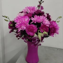 Pink and purple mixed flower arrangement in a bright pink vase
