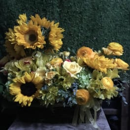 Yellow sunflowers and mixed blooms in a low basket arrangement