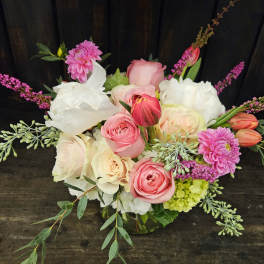 Pink and white mixed bouquet with roses, tulips, and dahlias in a glass vase