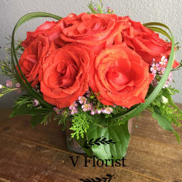Red rose bouquet with small pink filler flowers in a vase