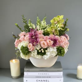Pink roses and orchids in a white bowl vase with white hydrangeas