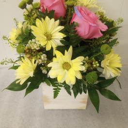 Pink roses and yellow daisies in a white square vase