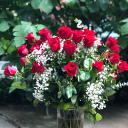 Bouquet of red roses and white baby's breath in a glass vase