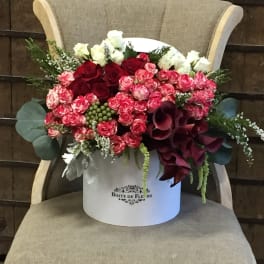 Bouquet of red and pink roses with white blooms in a white hatbox
