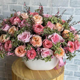 Pink and peach roses arranged in a white bowl vase