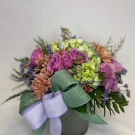 Bouquet of pink, purple, and yellow flowers with a lavender ribbon in a vase