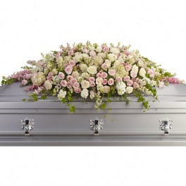 Pastel pink and white floral casket spray on a silver casket