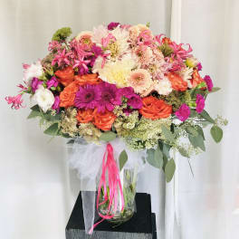 Large bouquet of pink, orange, and white flowers in a glass vase