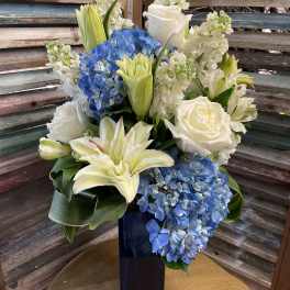 Blue and white floral arrangement in a tall dark vase