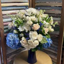 White and blue floral arrangement in a dark vase