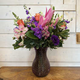 Pink and purple mixed bouquet in a dark glass vase