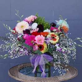 Colorful mixed bouquet in a glass vase with a purple ribbon