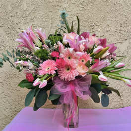 Pink mixed bouquet in a clear vase with a tulle bow