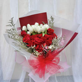 Bouquet of red roses and white tulips wrapped in red and white paper