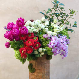 Large mixed bouquet with pink, red, white, and lavender flowers in a wooden container