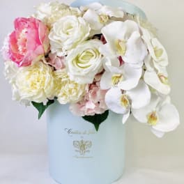 Pink and white flowers arranged in a pale blue hat box