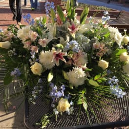 Large mixed floral arrangement with white lilies, roses, and blue flowers
