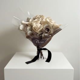 Bouquet of cream paper roses made from printed pages, wrapped in cellophane with brown paper and a black ribbon.