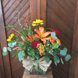Mixed bouquet in a glass vase with lilies, roses, and yellow daisies
