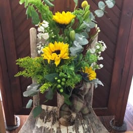 Tall bouquet with yellow sunflowers and mixed greenery in a rustic container
