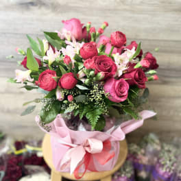 Pink and red rose bouquet in a pink wrapped container with ribbon
