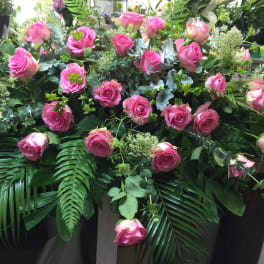 Large arrangement of pink roses with lush greenery