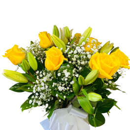 Yellow roses and lilies in a wrapped bouquet with baby's breath