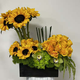 Yellow sunflowers and roses arranged in a black rectangular container