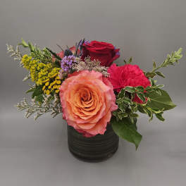 Mixed flower arrangement in a black vase with roses and carnations