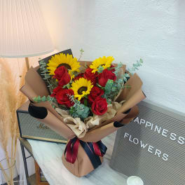 Bouquet of red roses and yellow sunflowers wrapped in brown paper