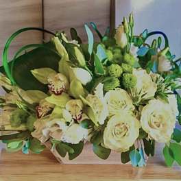 Cream roses and pale orchids in a low rectangular arrangement