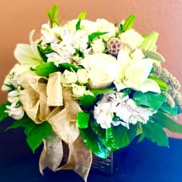 White floral arrangement with a gold ribbon in a dark vase