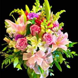 Pink roses and lilies in a glass vase with a pink ribbon