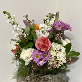 Mixed bouquet with pink, white, purple, and orange flowers in a dark vase