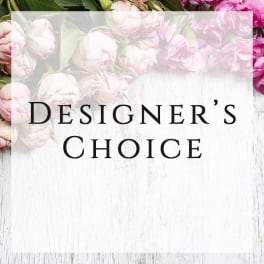 Designer’s Choice text over pink flowers on a white wood background