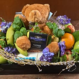 Gift basket with fruit, chocolates, and a teddy bear