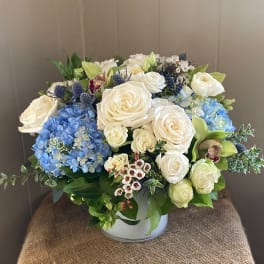 White roses and blue hydrangeas in a round vase
