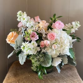 Mixed bouquet of pink and peach roses with white blooms in a glass vase