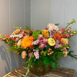 Colorful mixed flower arrangement in a glass vase on a wooden table