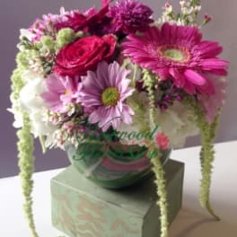 Pink and white mixed bouquet in a glass vase on a box
