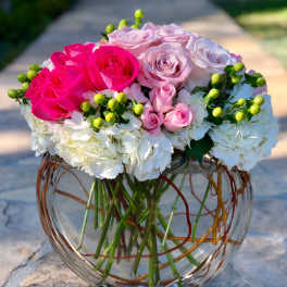 Pink and white roses in a round glass vase