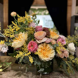 Mixed bouquet of peach, pink, and yellow flowers in a glass vase