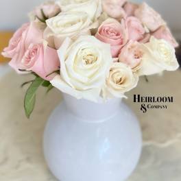 Pink and white roses arranged in a white vase