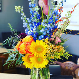 Colorful mixed bouquet in a clear glass vase with sunflowers and roses